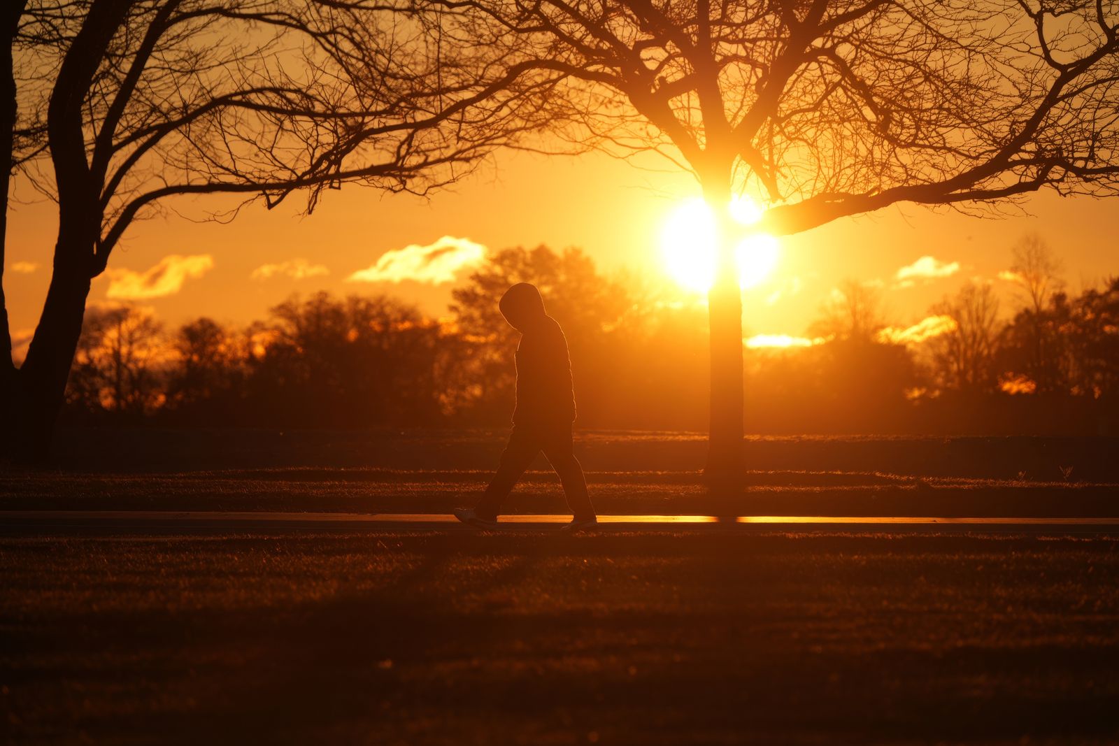 A person walking toward the sunrise on an open path